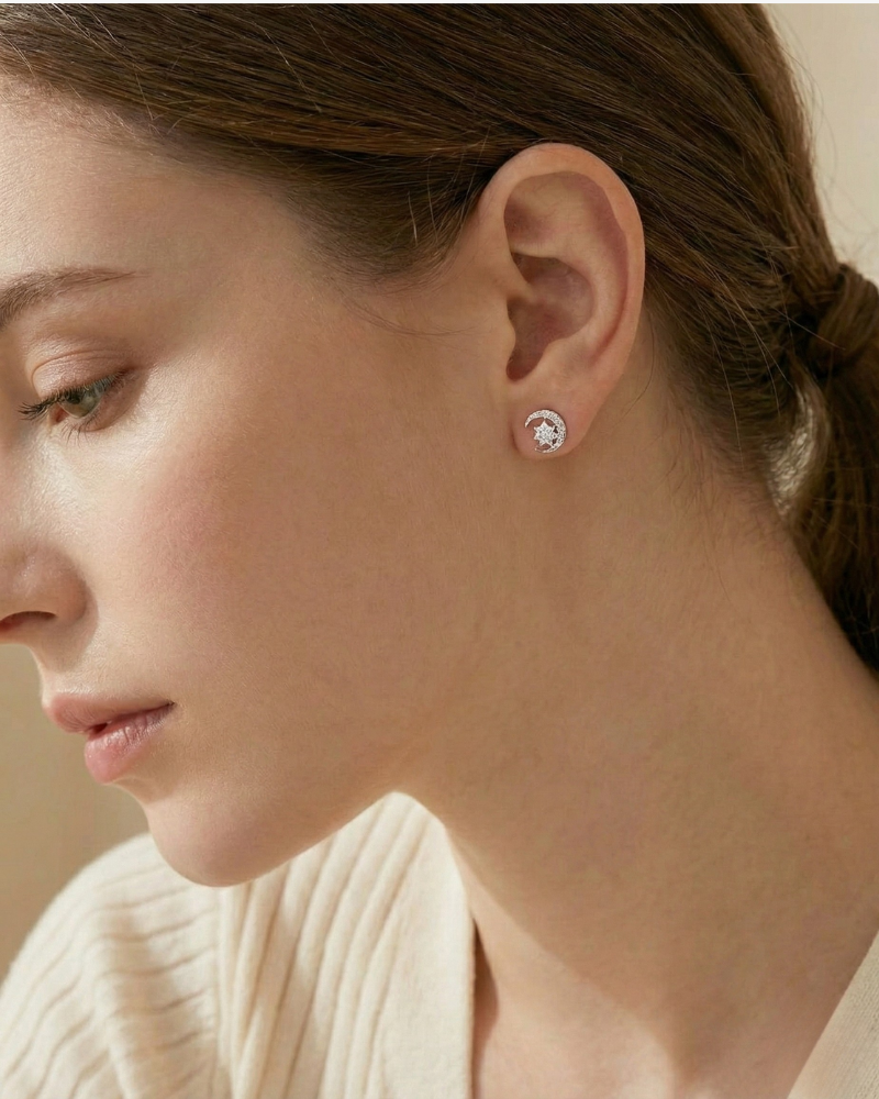 Close-up of a woman wearing diamond stud earrings with a neutral background