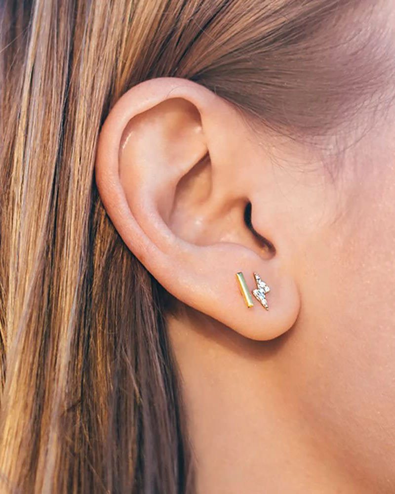 Close-up of an ear wearing two earrings with a blurred background