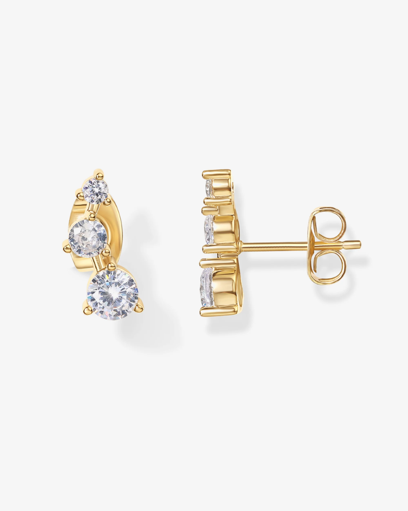 Gold earrings with clear gemstones on a white background