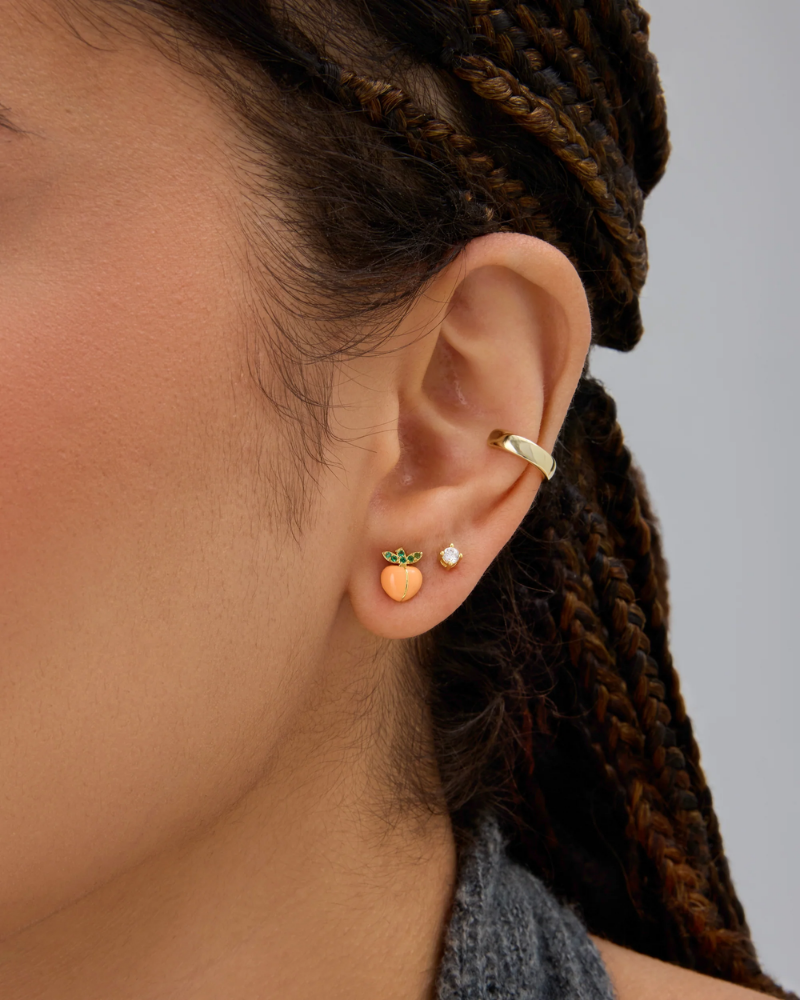 Close-up of an ear wearing gold earrings with a blurred background