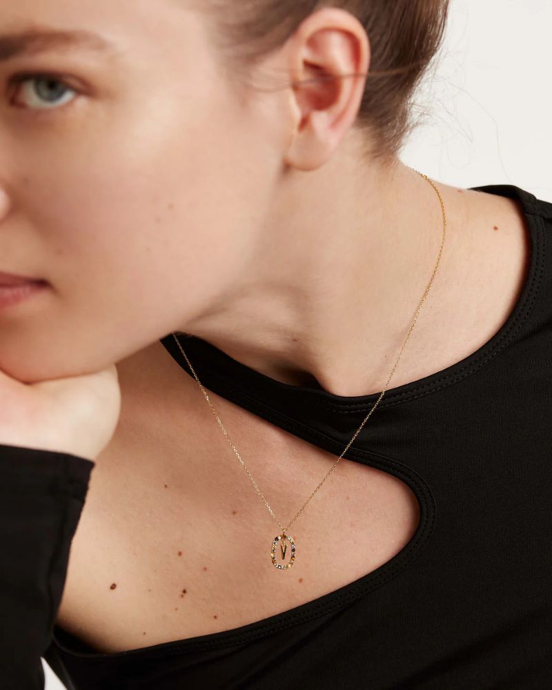 Close-up of a person wearing a delicate gold necklace with a small pendant.